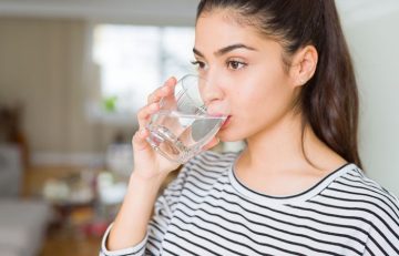 Woman hydrating lips by drinking water