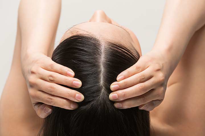 Woman massaging her scalp with camellia oil