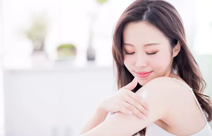 Woman moisturizing her skin to reduce stretch marks 