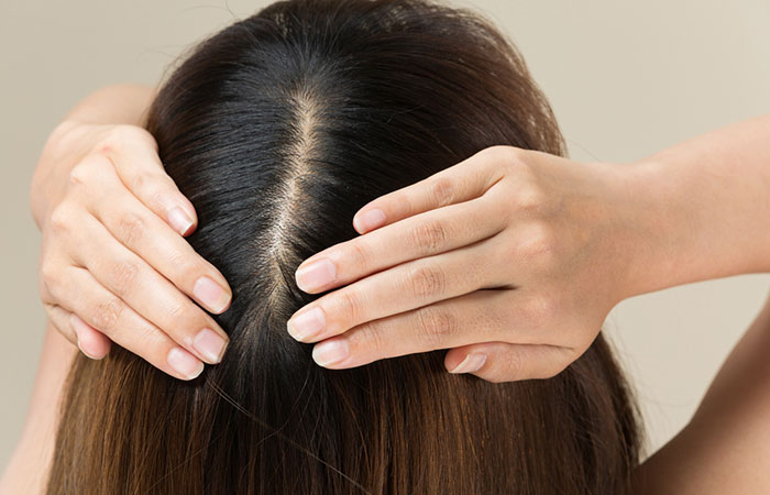 Woman parting her hair to reveal a healthy scalp as a potential benefit of asafoetida