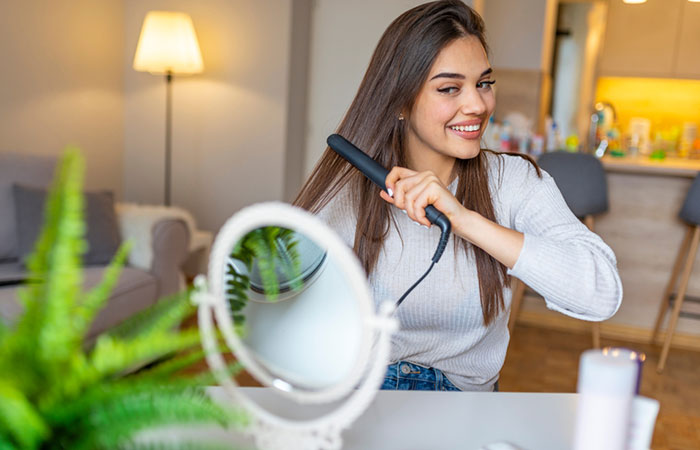 Woman straightening her hair at home