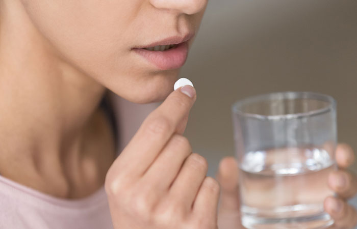 Woman taking prescribed pill to treat toenail fungus