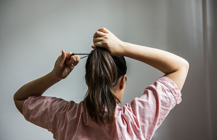 Woman tying hair tightly may observe hair fall