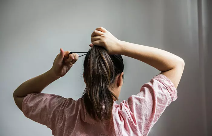Woman tying hair tightly may observe hair fall