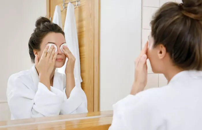 Woman uses cotton pads soaked wiith rose water to reduce eye puffiness