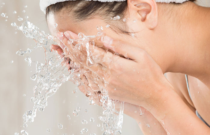 Woman washing her face to prevent acne between eyebrows.