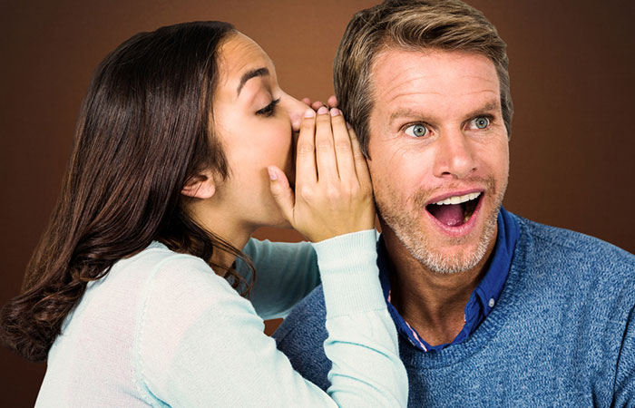 Woman whispering a secret into man's ear