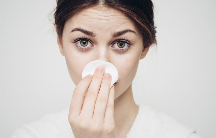 Woman wiping her nose with a cotton pad