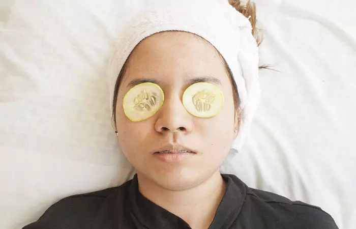 Woman with cucumber slices on eyes