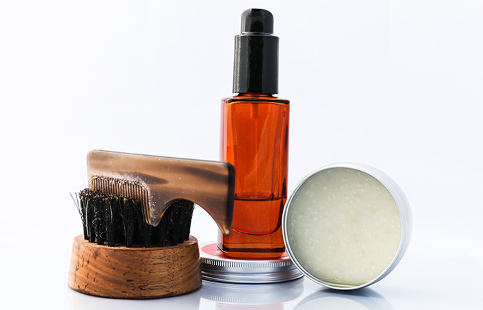 A group photo of beard balm, beard oil in a dropper, with two beard brushes