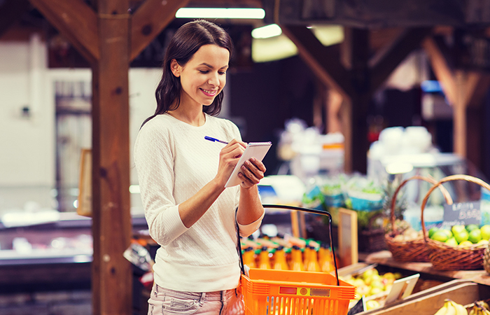 A happy woman following the volumetrics diet by checking off items from her grocery list
