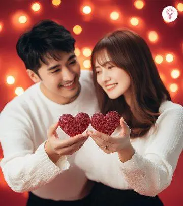 A young couple holding little hearts and looking at each other cheerfully