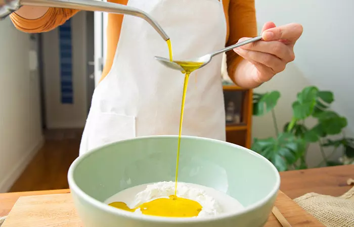 Woman measuring vegetable oil over flour for baking.