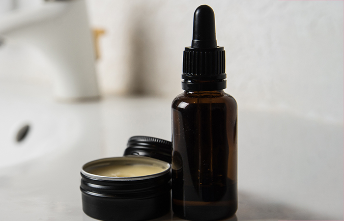 Beard oil in a brown dropper bottle with a beard balm in a black flat container