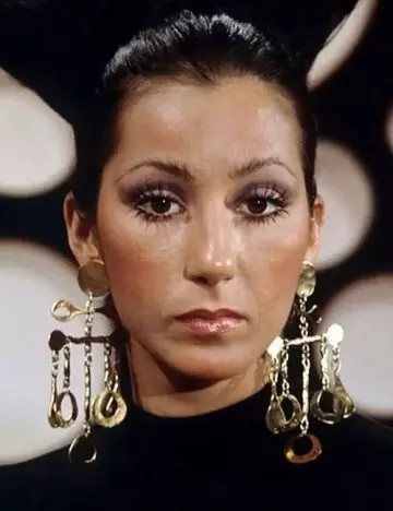 Cher posing with long lashes and golden earrings