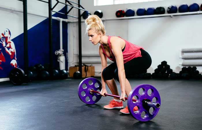 A woman doing a clean deadlift with a barbell