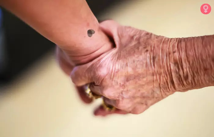 Close up of held hands with fingerprint heart minimalist mother son tattoo