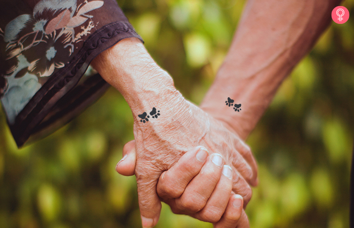 Close up of held hands with paw print minimalist mother son tattoo
