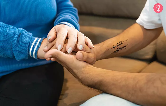 Close up of held pair of hands with matching biblical quotes mother son tattoo