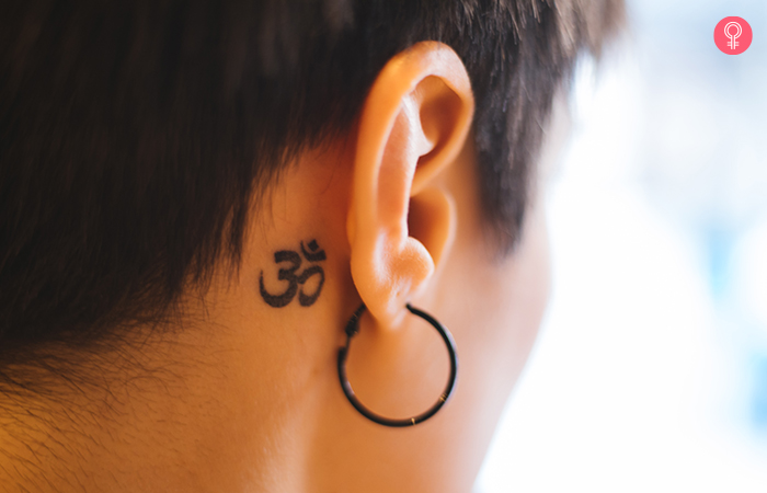 Close up of om symbol tattoo behind the ear for mother son tattoo inspiration