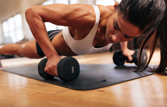 Woman doing dumbbell plank hold for EMOM Workouts