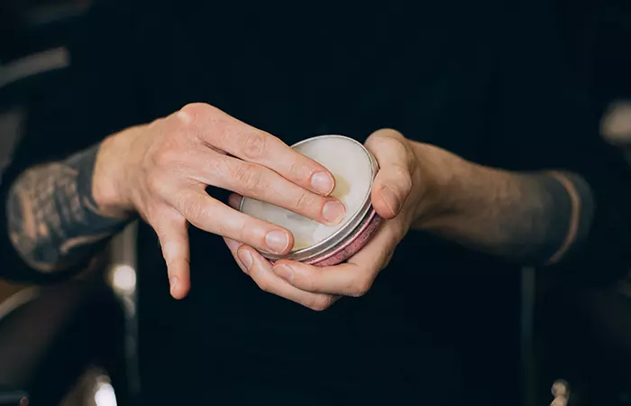 Fingers scooping up beard balm from its container