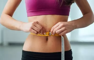 Following the runner’s diet helps a woman measuring her waist lose weight