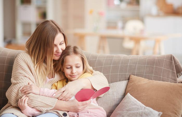 Mother and daughter sitting lovingly and reading a card.