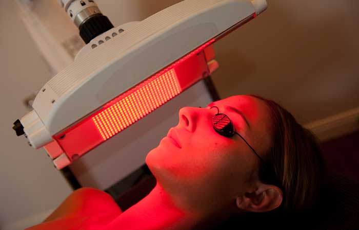 Woman undergoing red light therapy using a panel