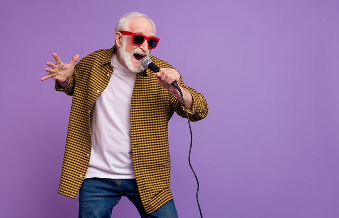 Energetic older adult singing karaoke at a 70th birthday party celebration