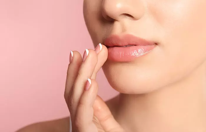 Woman applying nude lipstick to balance out the look