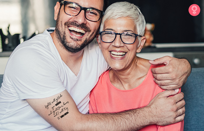 Man with song lyrics mother son tattoo on bicep embracing his mother