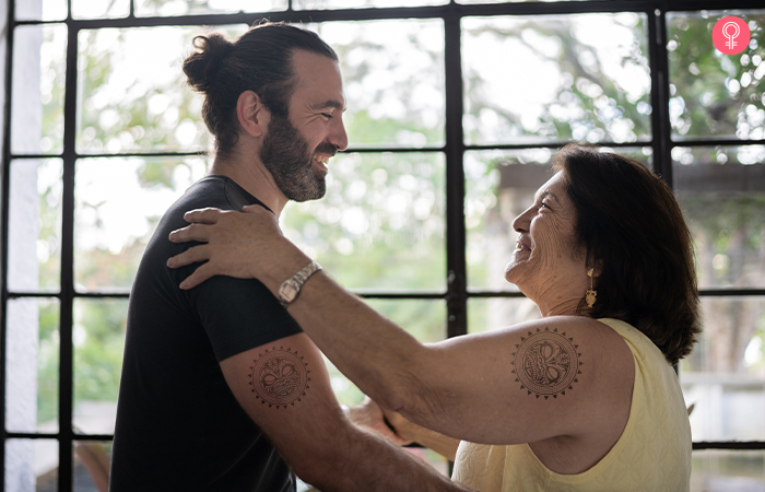 Mother and son with matching Tiki mother son tattoos embrace each other