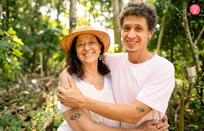 Mother and son with matching evil eye mother son tattoos pose in an embrace in a forest