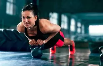 Woman doing single kettlebell push-ups for EMOM Workouts