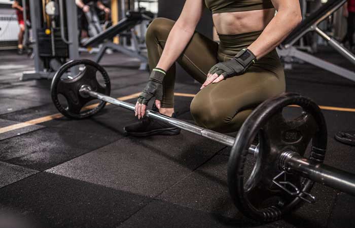 An athletic woman placing a barbell on the floor for sumo deadlifts