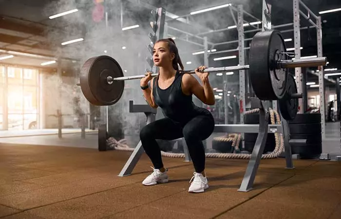 Woman performing back squats with a barbell for EMOM Workouts