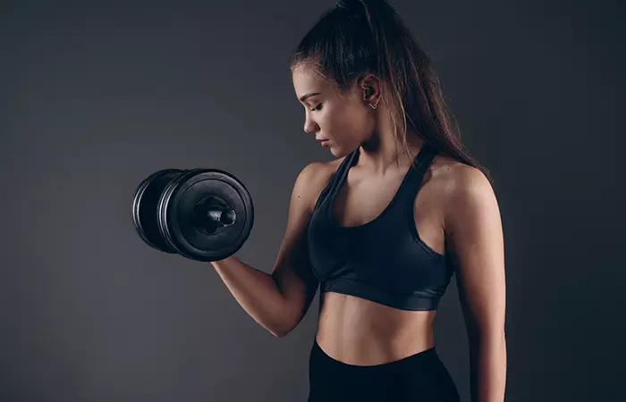 Woman performing open bicep curl exercise with dumbbells