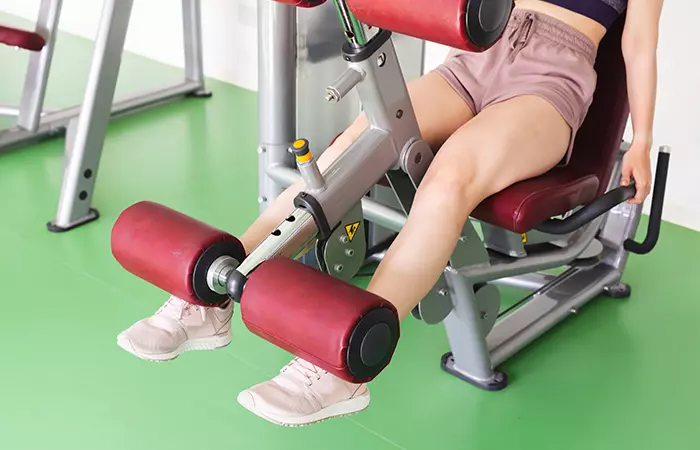 Woman performing open-chain seated leg extension exercise in the gym