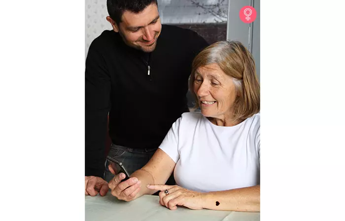 Woman with a heart mother son tattoo on her wrist showing her phone to her son