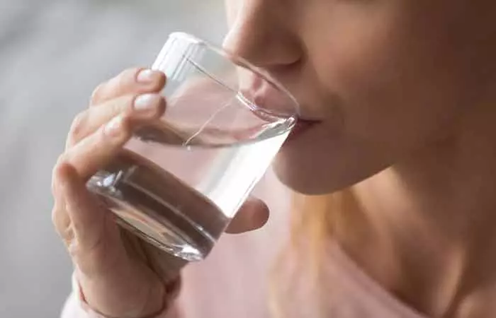 Woman drinking water to prevent wrinkled hands.