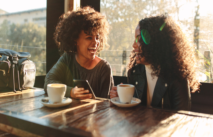 Two female friends chatting and having coffee together