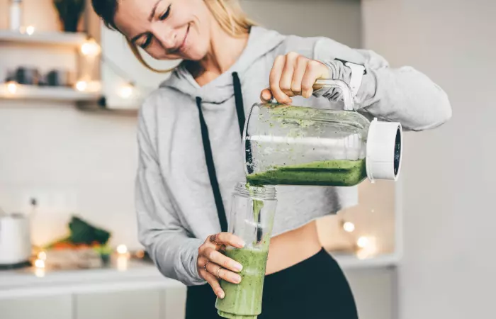 Woman prepares green smoothie for body reset diet