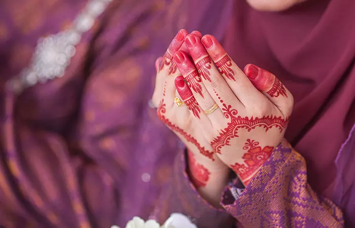 A Muslim woman with a henna tattoo praying