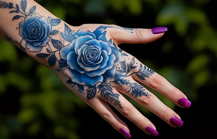 A blue rose artistic tattoo on the back of the hand