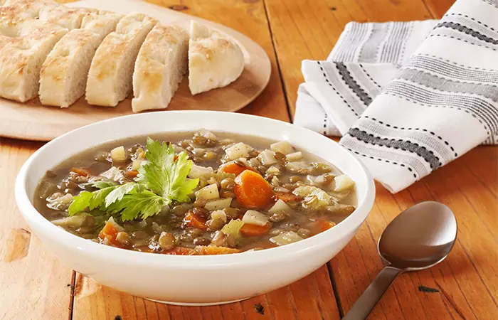 A bowl of mixed vegetable soup served with bread