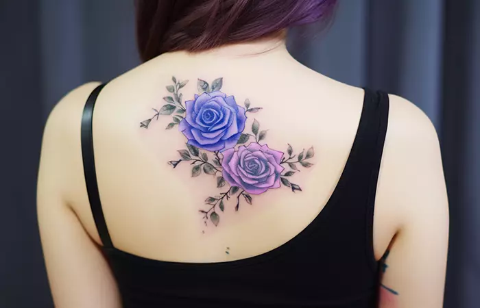 A fade-out watercolor blue and purple rose tattoo on the back