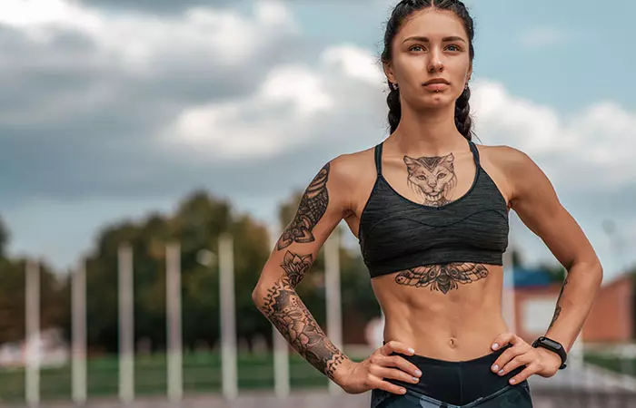 A fit woman with multiple tattoos in athleisure attire