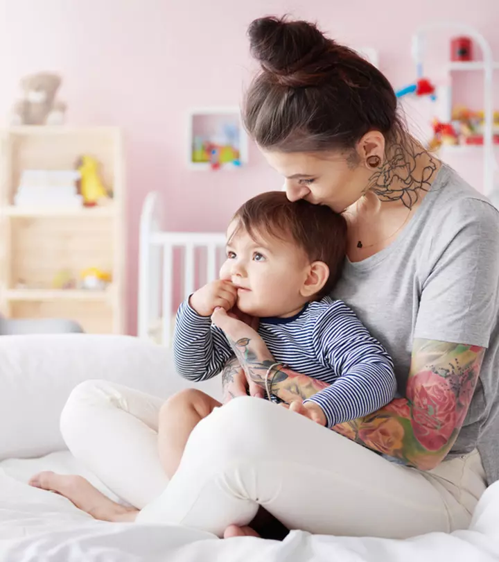 A nursing mother with a tattoo holding her baby
