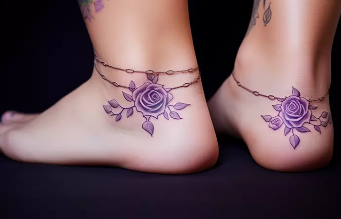 A pair of ornamental-style purple rose tattoos on the ankles